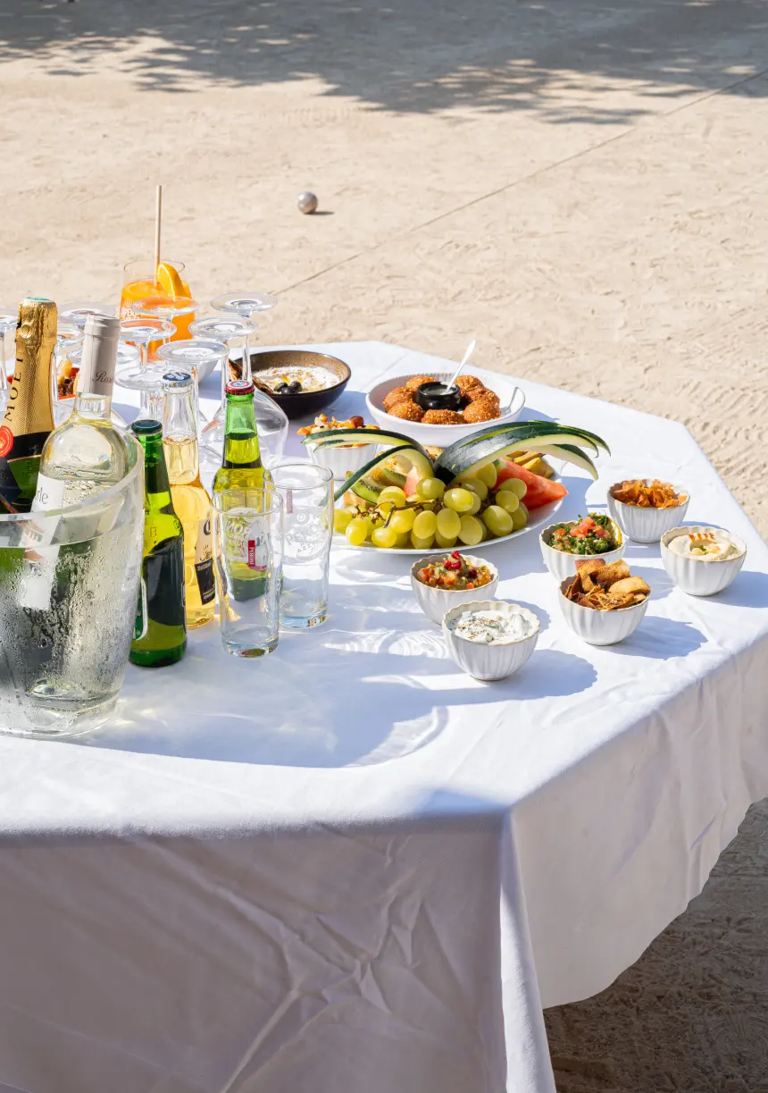 Table de banquet nappée de blanc, mezzés et apéritifs pour un groupe