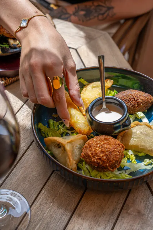 Assortiment de beignets libanais, un samboussek saisi à la main au-dessus du bol