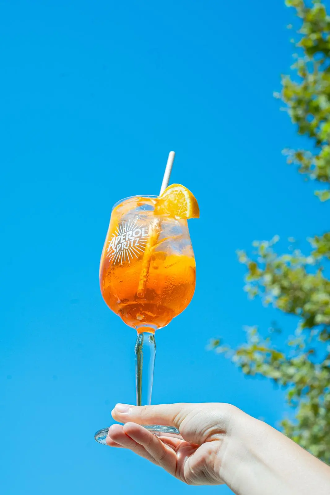 Verre d'apéritif levé devant un ciel bleu