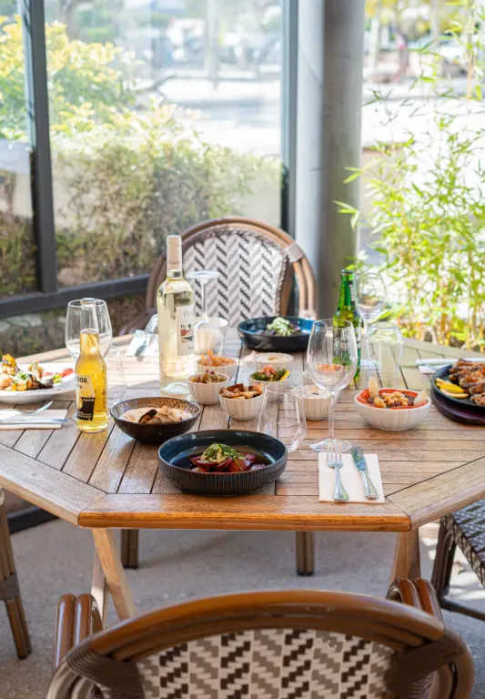 Table dressée devant la baie vitrée, mezzés à partager et vin blanc