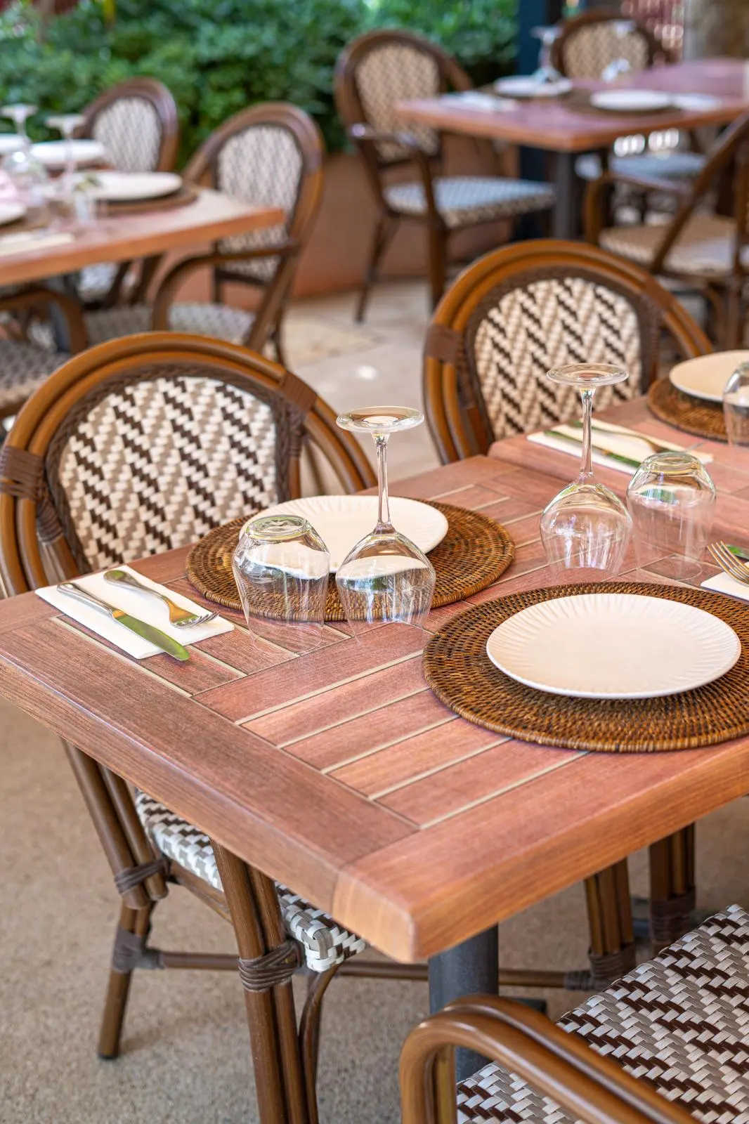 Terrasse du restaurant avec chaises en rotin et couverts prêts