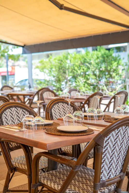 Terrasse abritée sous l'auvent, rangée de tables dressées
