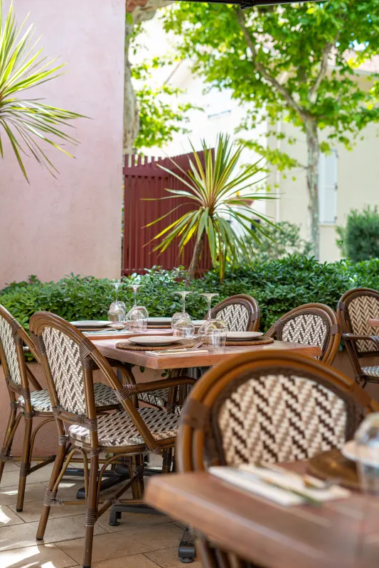 Terrasse du Byblos bordée de verdure, tables prêtes pour le service