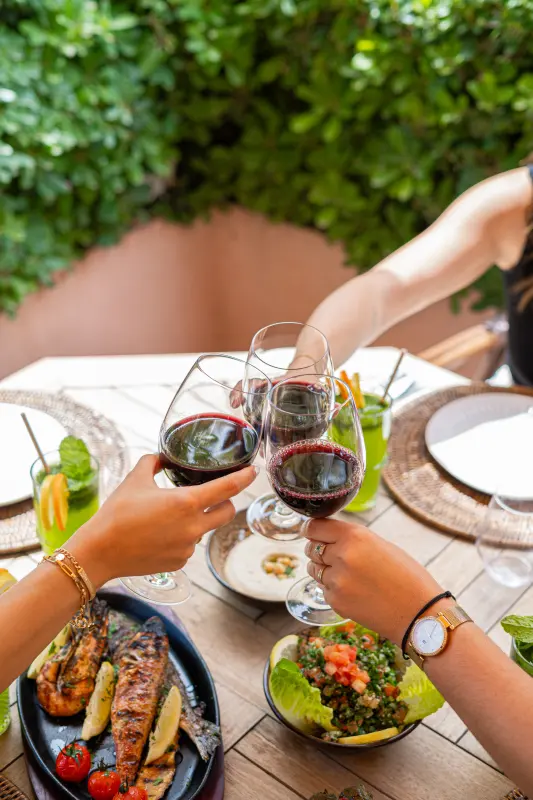 Trinquer au vin rouge autour d'une table de mezzés
